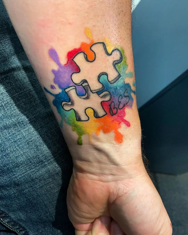 Autism puzzle pieces tattoo design for men and women, watercolor splash on forearm tattoo ideas
