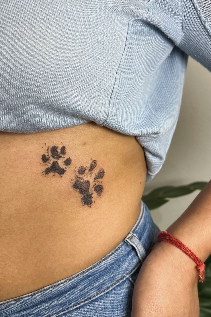 Blackwork paw print tattoo design for women on rib tattoo ideas