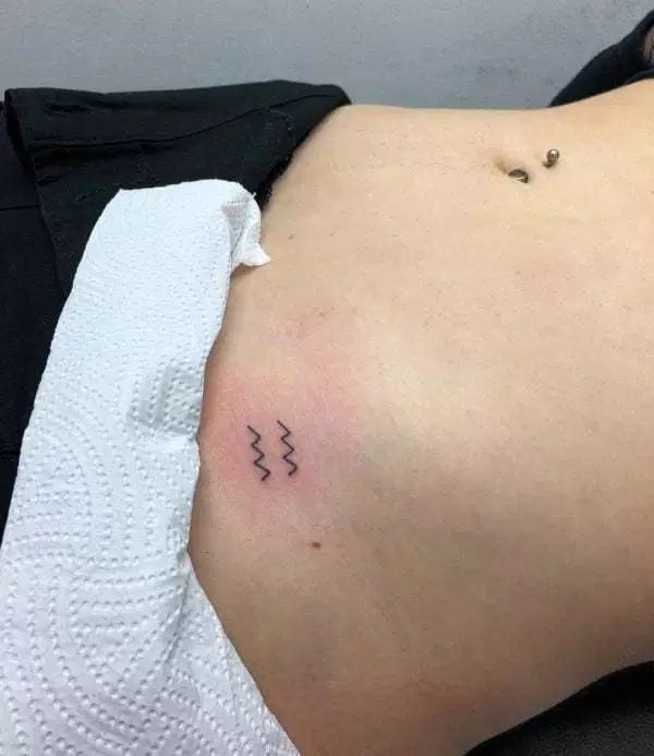 Fine line Aquarius symbol tattoo design for women on rib tattoo ideas