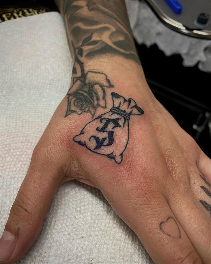 Money bag and rose tattoo design for men with black and grey style on hand tattoo ideas