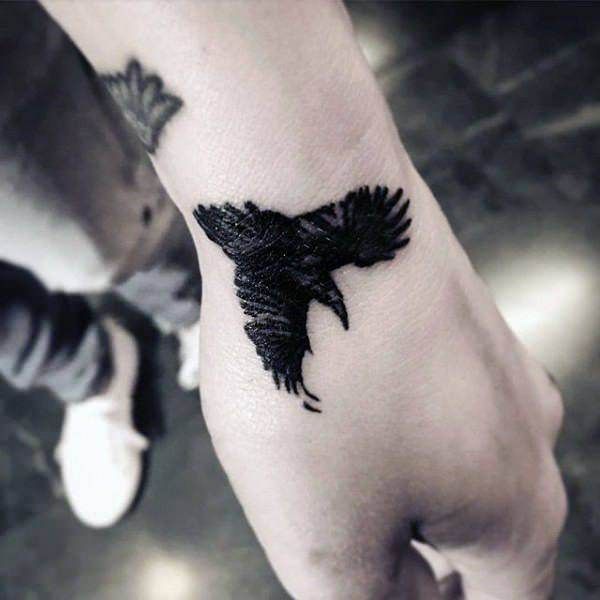 Blackwork raven tattoo design for men and women on wrist and hand tattoo ideas