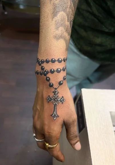 Realistic cross and religious tattoo design for men on wrist and hand tattoo ideas