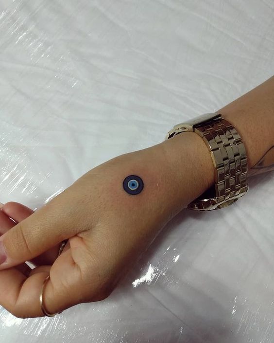 Minimalist evil eye tattoo design for women on hand and wrist tattoo ideas